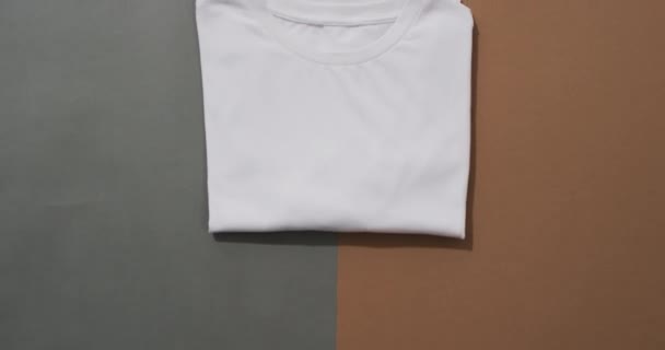 灰色と茶色の背景のコピースペースを備えた折り畳まれた白いTシャツの平らな層のビデオ ファブリック テクスチャ 材料コンセプト — ストック動画