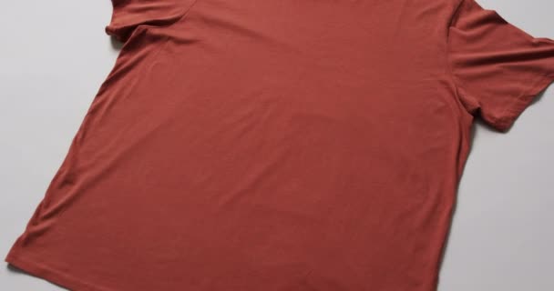 白い背景にコピースペースを持つオレンジ色のTシャツの平らな層のビデオ ファブリック テクスチャ 材料コンセプト — ストック動画