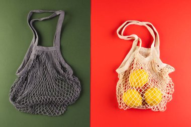 Limonlu kahverengi ve beyaz ağ torbaları ve kırmızı ve koyu yeşil arka planda kopya alanı. Alışveriş, çanta, renk, kumaş, doku ve malzeme kavramı.