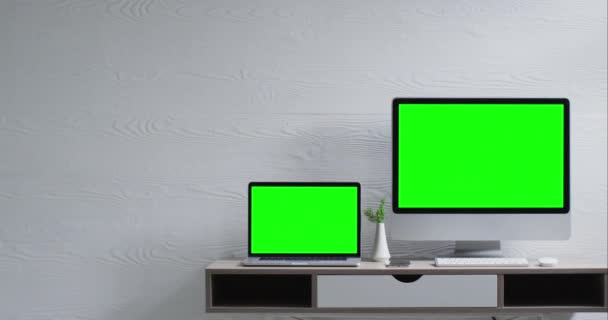 墙上安装了监视器和笔记本电脑 配有绿色屏幕和书桌 与白色纹理墙相对照 动作缓慢 家庭生活和通信 — 图库视频影像