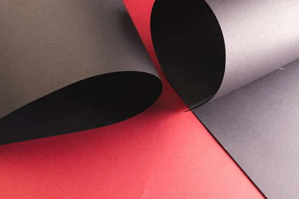 Close Van Opgerolde Stukjes Zwart Papier Met Kopieerruimte Rode Achtergrond — Stockfoto