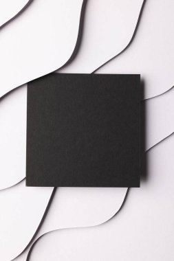 Beyaz arkaplanda beyaz kağıt dalgaları üzerinde kopyalama alanı olan siyah kağıdın dikey görüntüsü. Kağıt, yazı, doku ve malzeme kavramı.