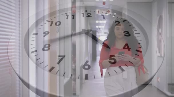 Animación Tictac Reloj Contra Mujer Biracial Hablando Smartphone Caminando Pasillo — Vídeos de Stock