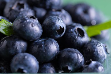 Yeşil zemin üzerinde fotokopi alanı olan yaban mersinlerinin mikro görüntüsü. Mikro fotoğrafçılık, meyve, yiyecek, doku ve renk kavramı.
