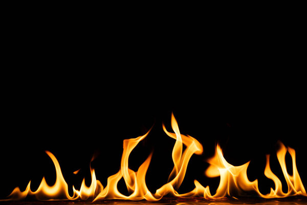 Yellow and orange flames and copy space on black background. Fire, flames, heat and light concept.