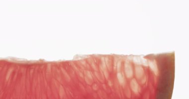 Beyaz arkaplanda kırmızı greyfurt diliminin fotokopi alanı olan mikro videosu. Mikro fotoğrafçılık, meyve, doku ve renk kavramı.