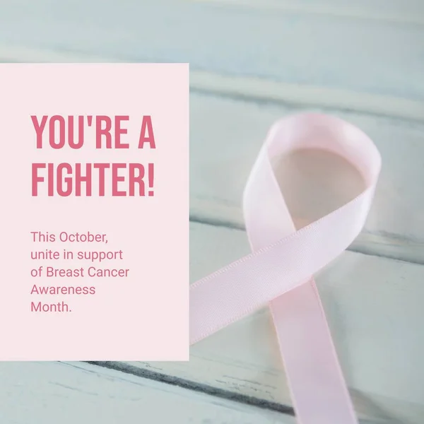 This october unite in support of breast cancer awareness month text and pink ribbon on table. Composite, you\'re a fighter, pink october, medical, healthcare, support and prevention concept.