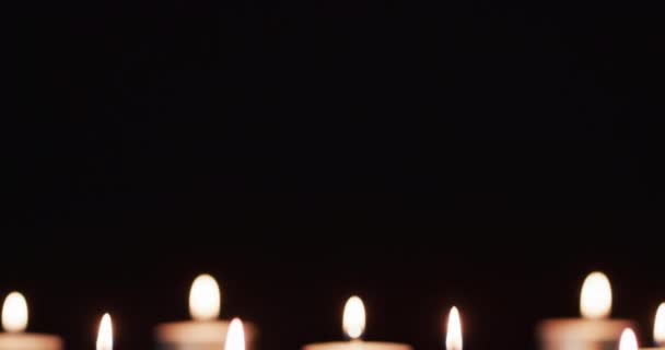 白い炎と黒い背景にスペースをコピーするティーキャンドルの列のビデオ 光のコンセプト — ストック動画