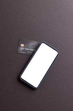 Boş ekranlı akıllı telefonun dikey görüntüsü ve siyah arka planda kredi kartı. Siber Pazartesi, siber alışveriş, perakende, teknoloji, elektronik cihaz ve iletişim konsepti.