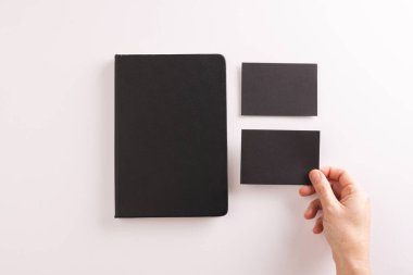Siyah defter ve beyaz arka planda siyah kağıt tutan beyaz kadın. Kağıt, yazı, doku ve malzeme kavramı.