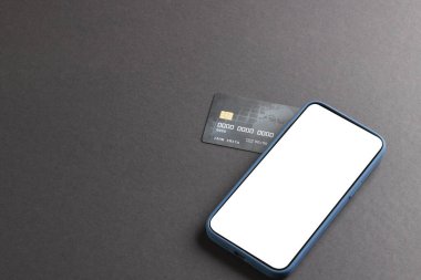 Beyaz ekranlı akıllı telefon ve siyah arka planda kredi kartı. Siber Pazartesi, siber alışveriş, perakende, teknoloji, elektronik cihaz ve iletişim konsepti.