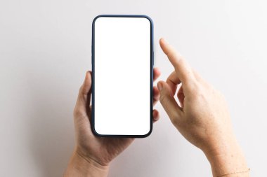 Kafkas kadının elleri elinde boş ekranlı akıllı telefon ve beyaz arka planda kopyalama alanı tutuyor. Siber teknoloji, elektronik cihaz ve iletişim konsepti.