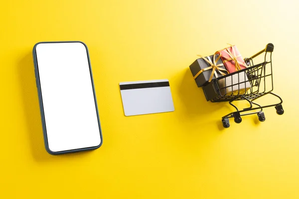 Kreditkarten Smartphone Mit Kopierplatz Und Einkaufswagen Mit Geschenken Auf Gelbem — Stockfoto