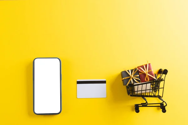 Kreditkarten Smartphone Mit Kopierplatz Und Einkaufswagen Mit Geschenken Auf Gelbem — Stockfoto