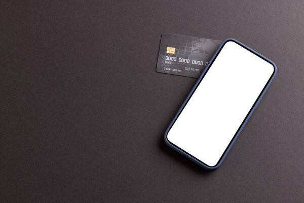 Smartphone with blank screen and credit card on black background. Cyber monday, cyber shopping, retail, technology, electronic device and communication concept.