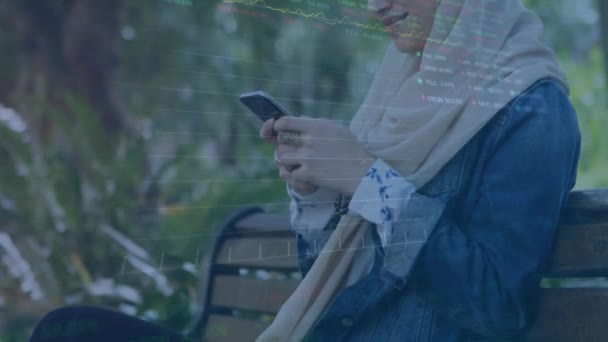 Анимация Обработки Биржевых Данных Над Бирасовой Женщиной Хиджабе Помощью Смартфона — стоковое видео