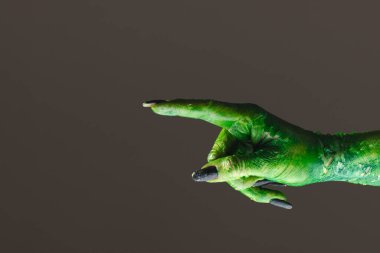 Gri arka planda parmağı olan siyah tırnaklı yeşil canavar eli. Cadılar Bayramı, gelenek ve kutlama konsepti.