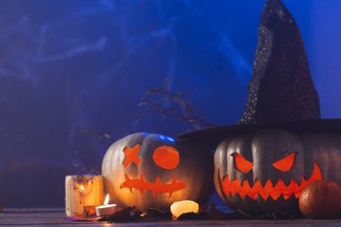 Mavi arka planda kopyalama alanı olan oyulmuş balkabakları ve mumlar. Sonbahar, sonbahar, cadılar bayramı, gelenek ve kutlama konsepti.