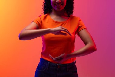 Neon pembesi ile turuncu arkaplanı gösteren melez bir kadın. Teknoloji, dijital ağlar, küresel bağlantılar ve iletişim metaevreleri.