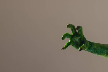 Gri arka plana uzanan siyah tırnaklı yeşil canavar eli. Cadılar Bayramı, gelenek ve kutlama konsepti.