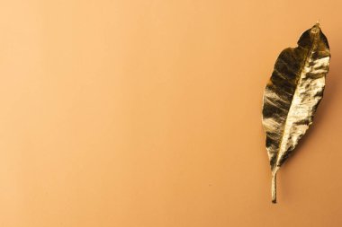 Turuncu arka planda kopyalama alanı olan metalik altın sonbahar yaprağı. Sonbahar, sonbahar, cadılar bayramı, gelenek ve kutlama konsepti.