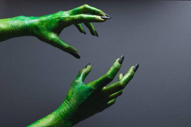 Siyah tırnaklı yeşil canavar elleri gri arka planda jest yapıyor. Cadılar Bayramı, gelenek ve kutlama konsepti.