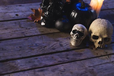 Kabaklar, kafatası ve mumlar. Kahverengi arka planda fotokopi alanı var. Sonbahar, sonbahar, cadılar bayramı, gelenek ve kutlama konsepti.