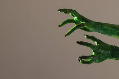 Gri arka plana uzanan siyah tırnaklı yeşil canavar elleri. Cadılar Bayramı, gelenek ve kutlama konsepti.