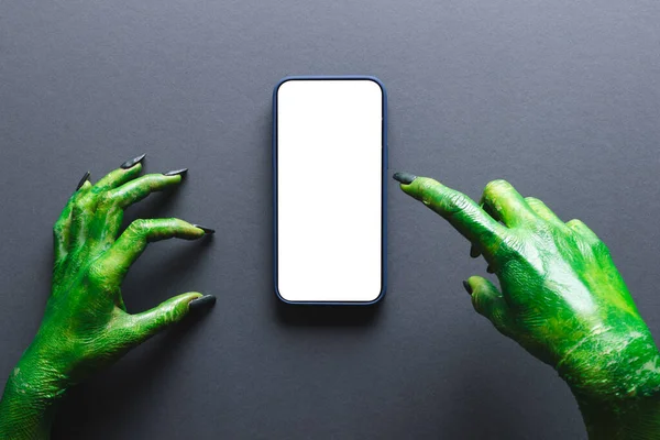 绿色怪物的手在智能手机上指向灰色背景的复制空间 万圣节 传统和庆祝概念 — 图库照片