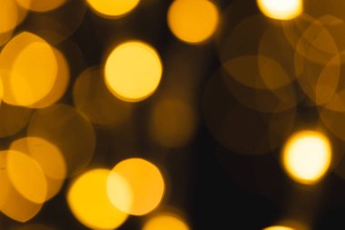 Koyu arkaplanda kopyalama alanı olan çoklu sarı bokeh ışıkları. Işık, renk ve şekil kavramı dijital olarak oluşturuldu.