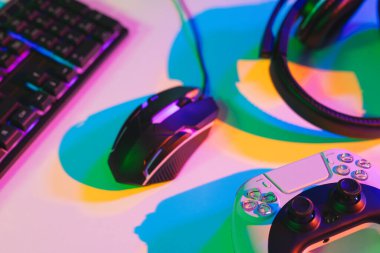 Bilgisayar klavyesinin bilgisayar oyunu aksesuarları ile neon arkaplanda kopyalama alanı ile birleşimi. Video oyunu ve dijital bağlantılar konsepti dijital olarak oluşturulmuş görüntü.