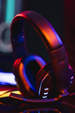 Neon arka planda kopya alanı olan video oyunu kulaklıklarının dikey görüntüsü. Video oyunu ve dijital bağlantılar konsepti dijital olarak oluşturulmuş görüntü.