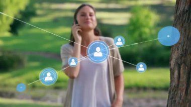 Parkta akıllı telefondan konuşan mutlu beyaz kadın üzerinden profil ikonları ağı animasyonu. Küresel ağ ve iş teknolojisi kavramı