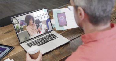 Kafkasyalı iş adamı, ekranda Afro-Amerikan bayan meslektaşıyla görüntülü konuşma yapıyor. Çevrimiçi bağlantılar, iş ve ağ oluşturma kavramı.