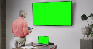 Kafkasyalı iş adamı yeşil ekran TV ekranı ile görüntülü görüşme yapıyor. Çevrimiçi bağlantılar, iş ve ağ oluşturma kavramı.
