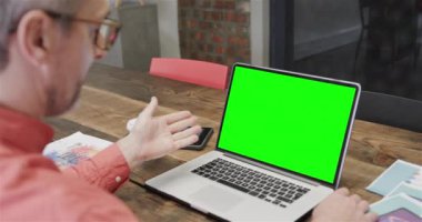 Kafkasyalı iş adamı yeşil ekranlı bir laptopla görüntülü görüşme yapıyor. Çevrimiçi bağlantılar, iş ve ağ oluşturma kavramı.
