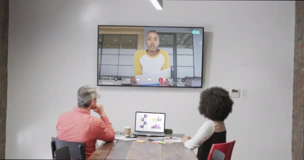 テレビのスクリーンでアフリカ系アメリカ人男性の同僚とのビデオ通話の多様なビジネスマン オンライン接続 ビジネス ネットワーキングコンセプト — ストック動画