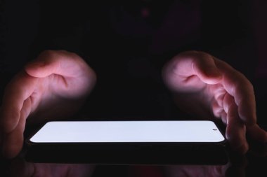 Kopyalama alanı, parlak ışık ekranı ve siyah arka planda beyaz elleri olan tablet. Video oyunu ve dijital bağlantılar konsepti dijital olarak oluşturulmuş görüntü.