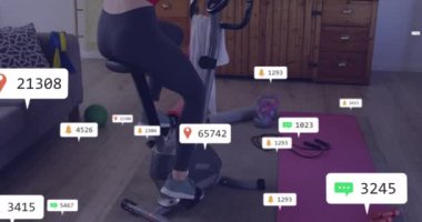 Kafkasyalı bir kadının televizyon izlerken bisiklet sürmesi ile ilgili uyarı barlarının canlandırılması. Dijital bileşik, çoklu pozlama, sosyal medya hatırlatıcısı, egzersiz, ev çalışması ve fitness konsepti.