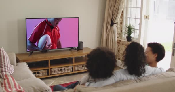 Бирациальная Семья Смотрит Телевизор Африканским Американским Игроком Регби Мячом Экране — стоковое видео