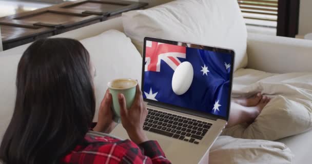 一个女人在屏幕上看带有橄榄球的笔记本电脑 屏幕上挂着澳大利亚国旗 通信技术 旗帜和体育 数字合成录像 — 图库视频影像