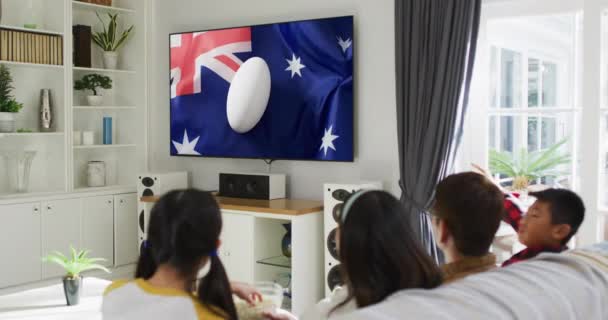 亚洲家庭正在收看电视屏幕上印有澳大利亚国旗的橄榄球球 通信技术 旗帜和体育 数字合成录像 — 图库视频影像