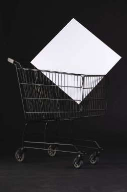 Boş tuvalli alışveriş arabasının dikey görüntüsü ve siyah arkaplan üzerine kopyalama alanı. Siber Pazartesi, Kara Cuma, çevrimiçi alışveriş, nakliye ve küresel bağlantılar kavramı.