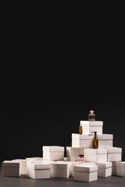 Vertical image of boxes with beauty products and copy space over black background. Cyber monday, black friday, online shopping, shipping and global connections concept.