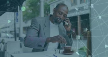Afro-Amerikan bir adamın bir kafede akıllı telefondan konuşması üzerine tıbbi simgelerin dünya animasyonu. Küresel ağ ve tıbbi araştırma teknolojisi kavramı
