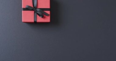 Kırmızı hediye paketi ve kurdeleli hediye etiketlerinin videosu ve siyah arka planda kopyalama alanı. Siber Pazartesi, Kara Cuma, çevrimiçi alışveriş, nakliye ve küresel bağlantılar kavramı.
