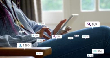 Evde dijital tablet kullanan bir kadının orta kesiminde yüzen sosyal medya simgelerinin canlandırılması. Sosyal medya ağı ve iş teknolojisi kavramı