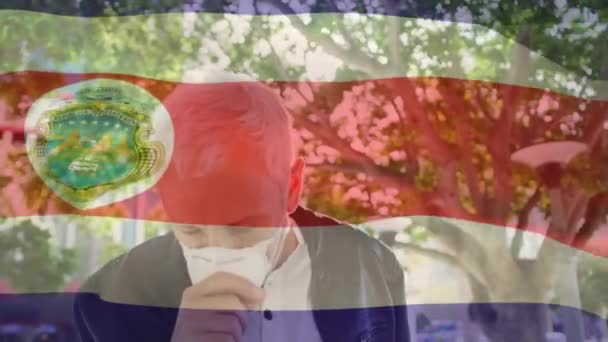 ストリートで咳をするマスクを着用した白人男性に対するコスタリカの旗を振るアニメーション 世界的なコビド 19パンデミックコンセプト — ストック動画