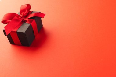 Kırmızı kurdeleli siyah hediye kutusu ve kırmızı arkaplanda kopyalama alanı. Siber Pazartesi, Kara Cuma, çevrimiçi alışveriş, nakliye ve küresel bağlantılar kavramı.