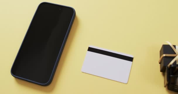 白い画面 クレジット カード 黄色の背景のショッピング トロリーが付いているスマートフォンのビデオ サイバーショッピング オンライン配送 テクノロジー グローバルコネクションのコンセプト — ストック動画
